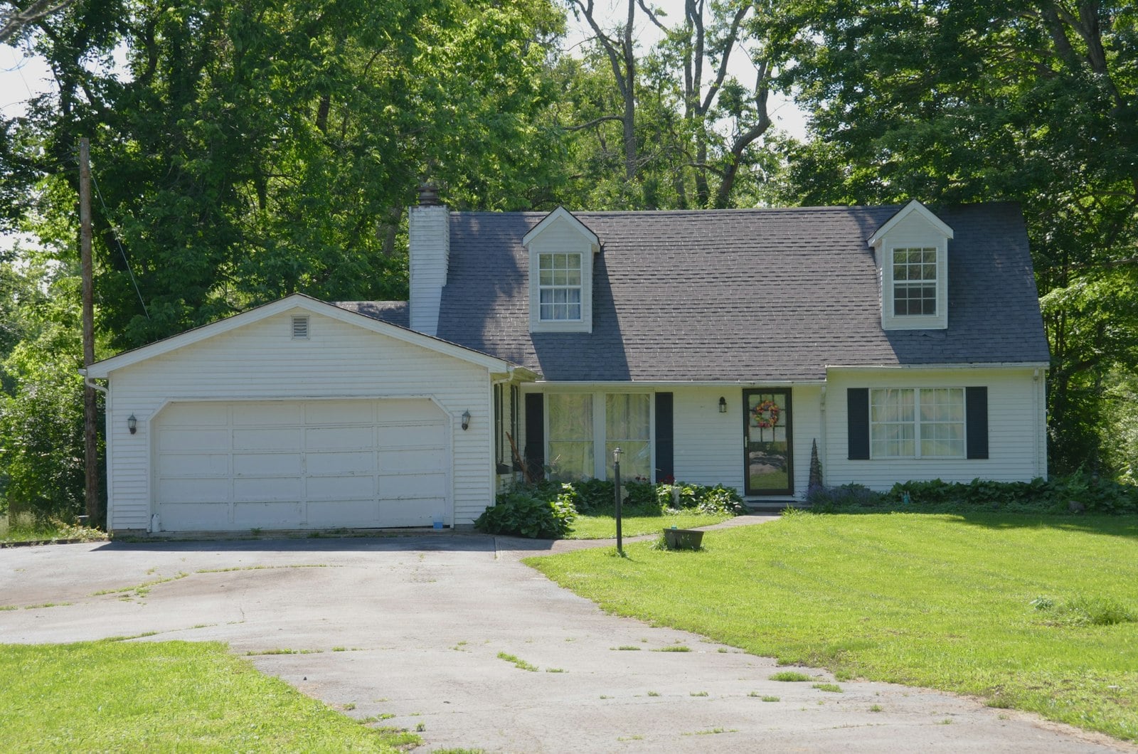 White house with a driveway and green lawn